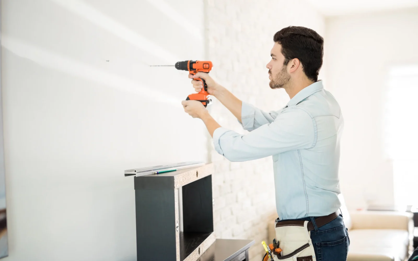 profile-view-good-looking-young-handyman-making-some-drill-holes-wall-installing-shelf